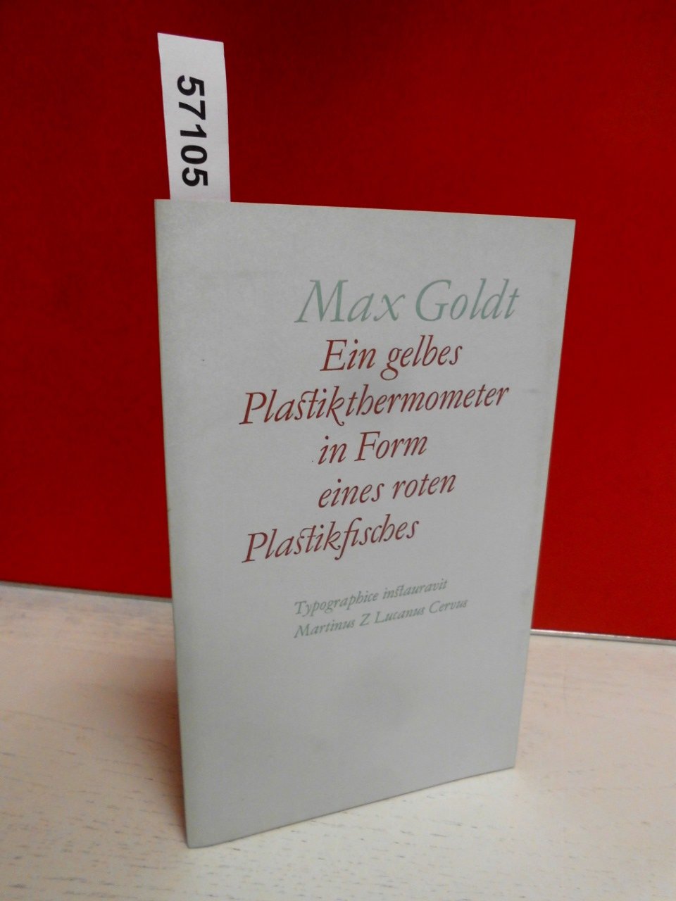 Ein gelbes Plastikthermometer in Form eines roten Plastikfisches Books